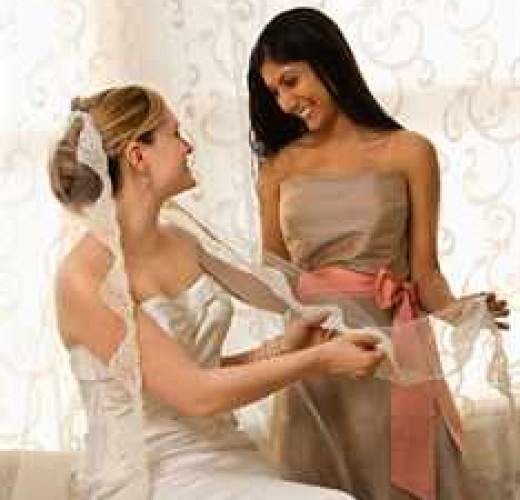 Indian maid of honor holding Caucasian bride's veil.